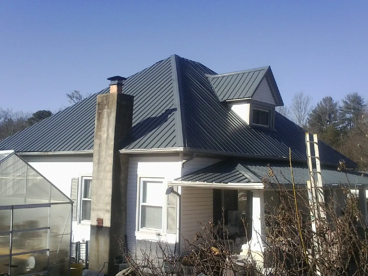 Dark blue standing seam metal roof on a white farmhouse with dormer — Slate & Tile Roof Repair by Roofing Brothers in Broad Top