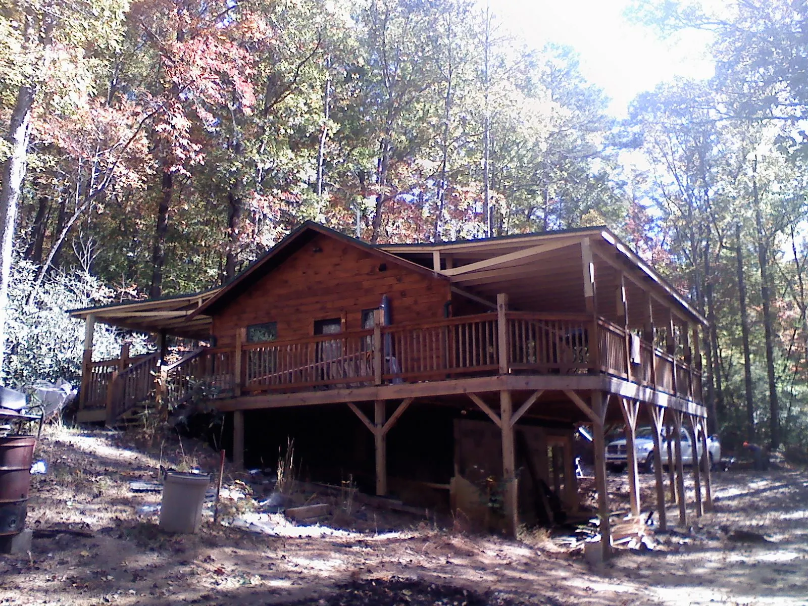 Log cabin with a wraparound porch and metal roof in the fall in Broad Top