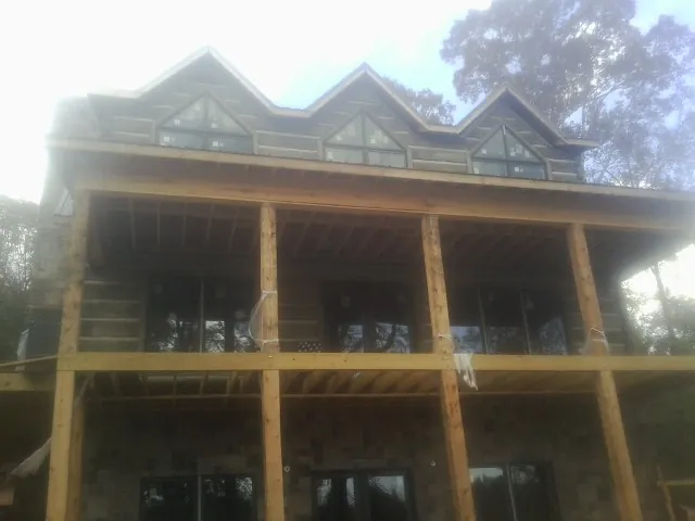 Dormers and porch framing on a large log home under construction — Roof Coating work by our crew in Broad Top