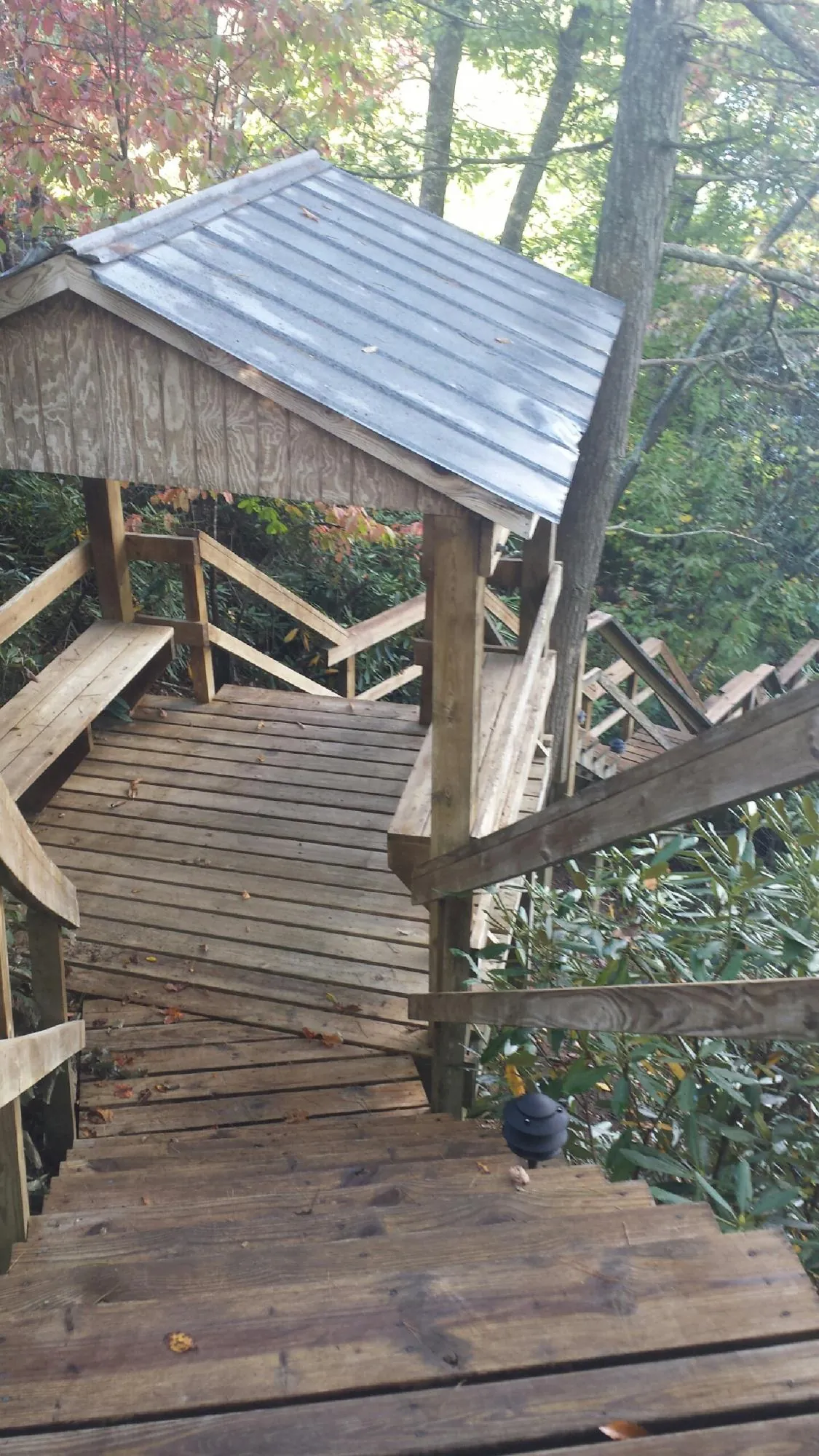 Metal roofed shelter over wooden steps on a wooded walkway — Skylight Repair & Installation work by our crew in Broad Top