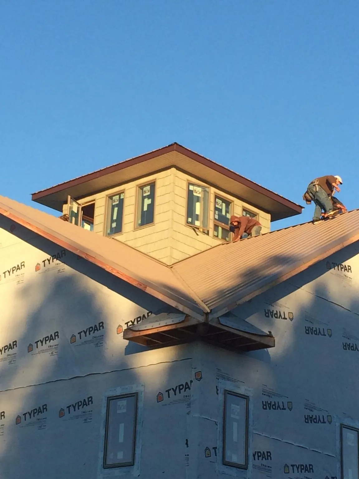 Roofers working around a rooftop cupola on a new metal roof at sunset — Roof Waterproofing in Broad Top by Roofing Brothers